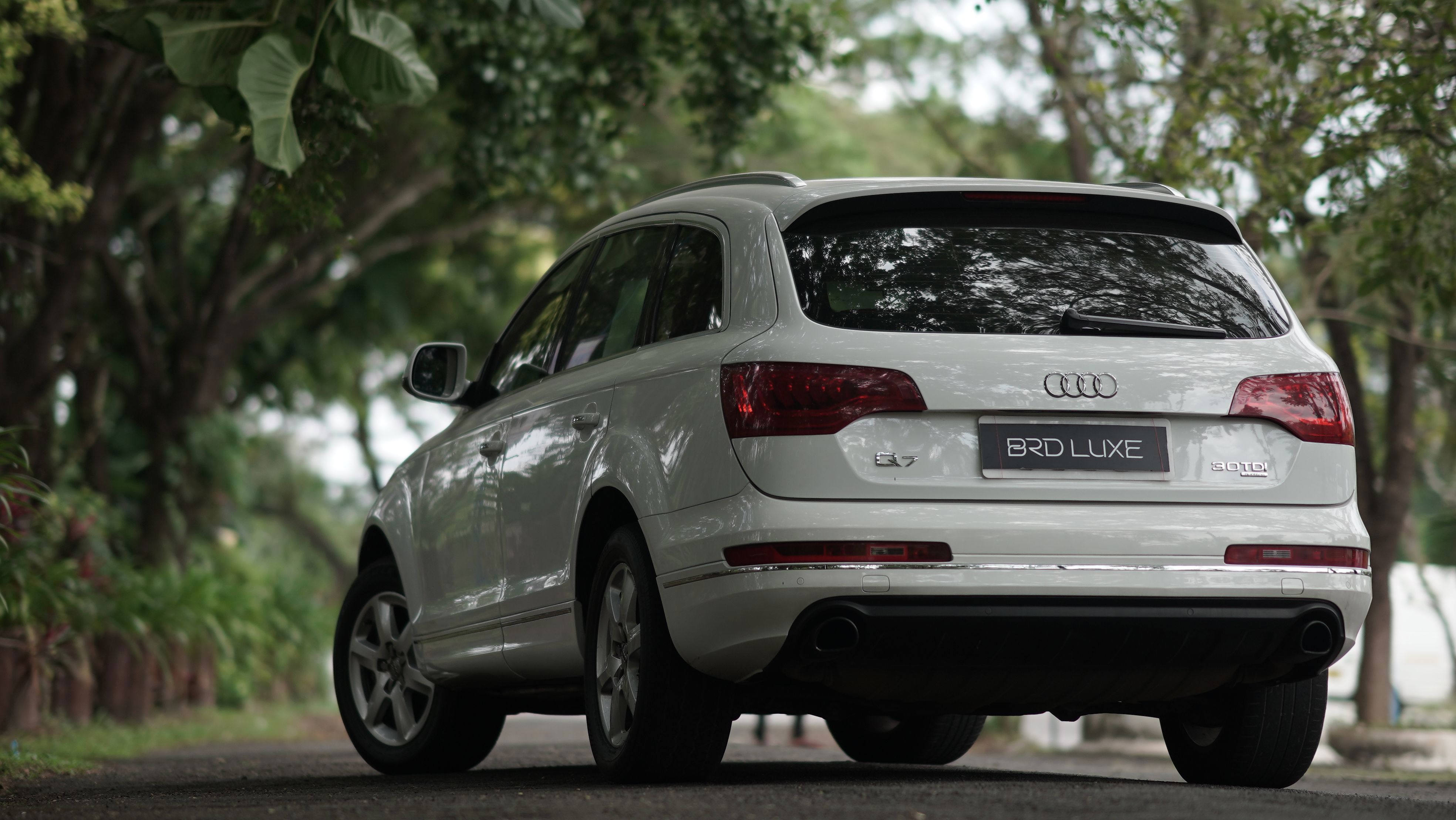 Audi Q7 SUV in Weiß auf einer Landstraße mit Grünfläche