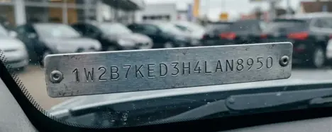 Nahaufnahme der 17-stelligen Fahrgestellnummer hinter der Windschutzscheibe eines Fahrzeugs bei Tageslicht