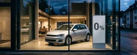 Autohaus-Schaufenster mit einem Aktionsschild für eine Null-Prozent-Finanzierung neben einem Neuwagen