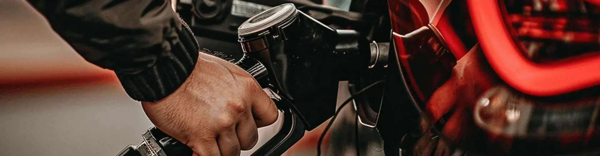 Person betankt rotes Auto an einer Zapfsäule mit Super E10 Kraftstoff