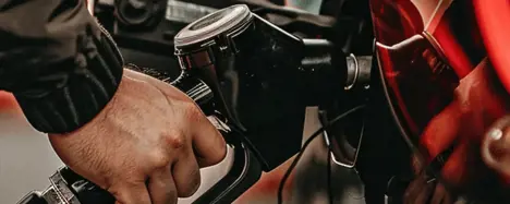 Person betankt rotes Auto an einer Zapfsäule mit Super E10 Kraftstoff