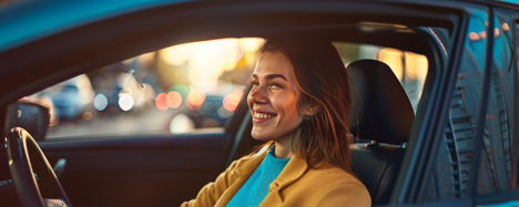 Gebrauchtwagenkauf Frau sitzt glücklich lächelnd im Auto