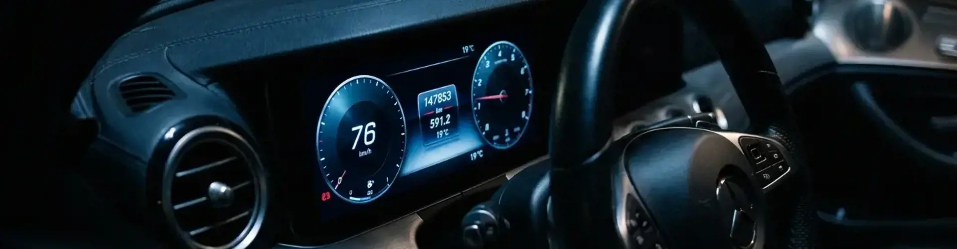 Nahaufnahme eines digitalen Kombiinstruments im Auto mit Kilometerstand bei dramatischer seitlicher Beleuchtung