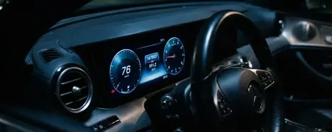 Nahaufnahme eines digitalen Kombiinstruments im Auto mit Kilometerstand bei dramatischer seitlicher Beleuchtung