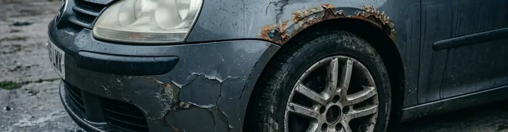 Gebrauchtwagen mit Rost und abblätterndem Lack bei Regen