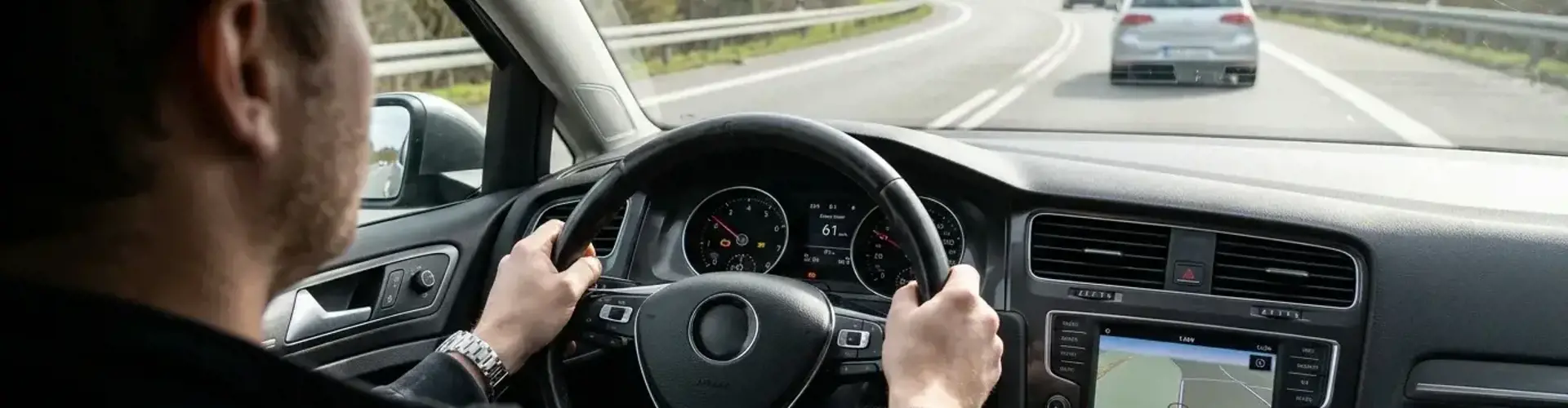 Konzentrierter Fahrer im Cockpit eines Gebrauchtwagens während einer Probefahrt, Hände am Lenkrad, Blick auf die Straße